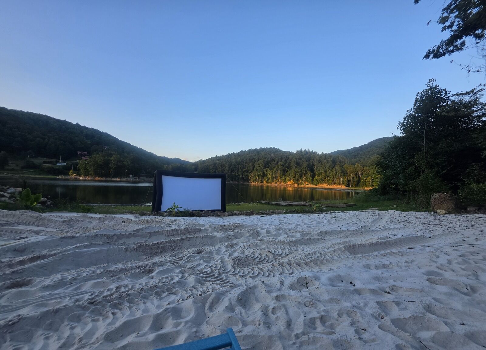 Outdoor movie screen set up on the white-sand beach at dusk